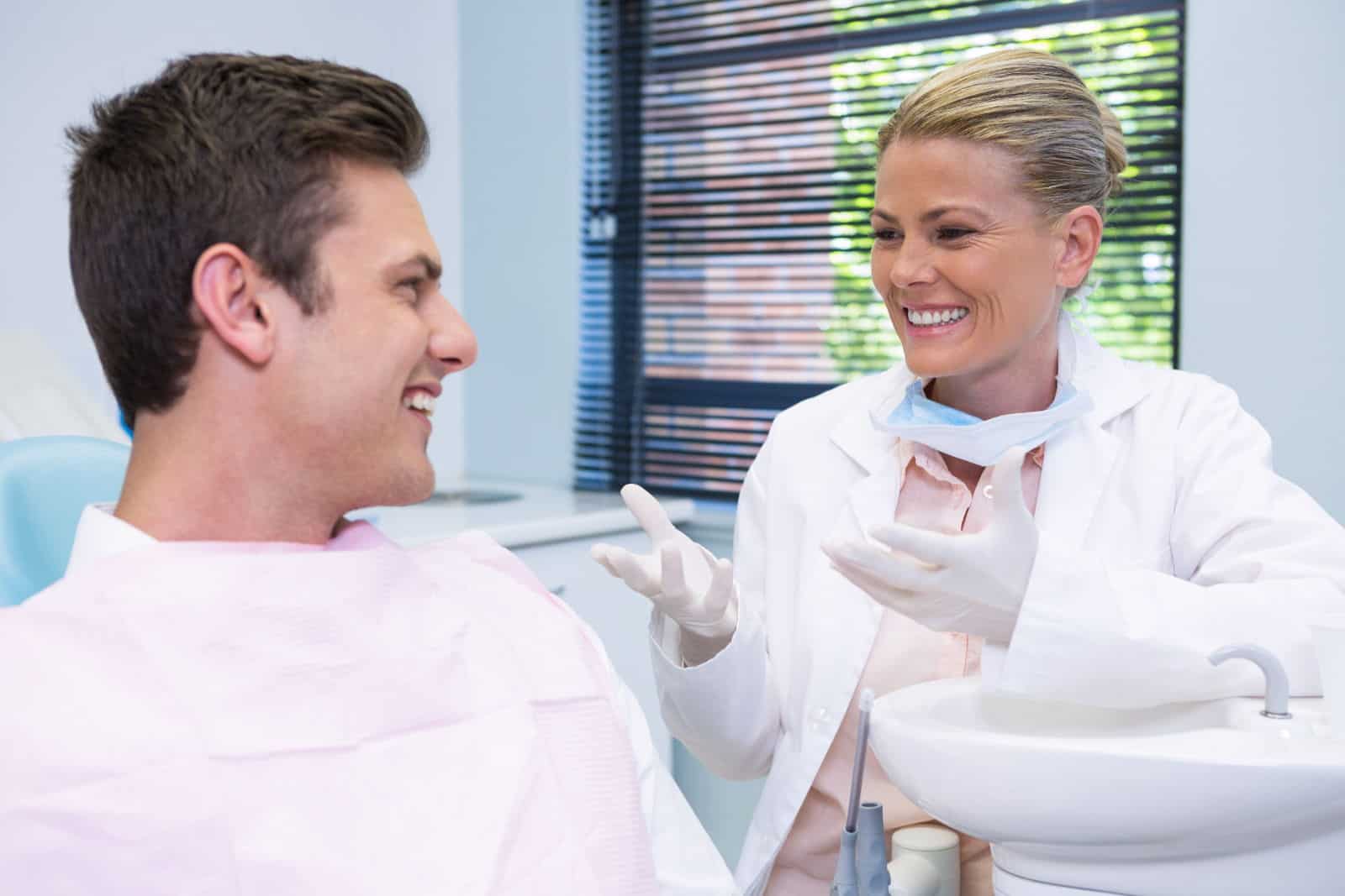A dentist and patient smile at each other as the dentist explains the patient's cosmetic dental options.