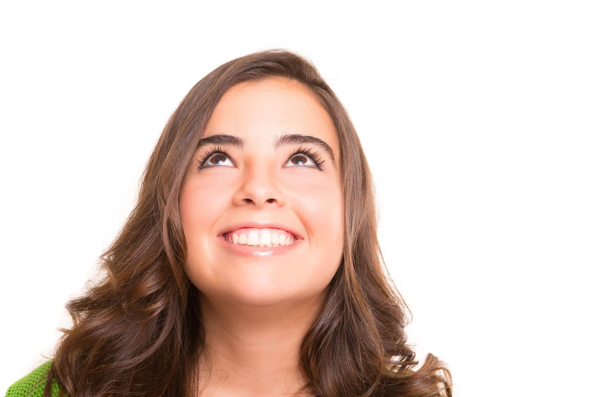 A woman with perfect teeth smiles and looks up in front of a white background.