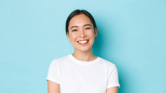 A young woman smiling and showing off her new porcelain veneers.