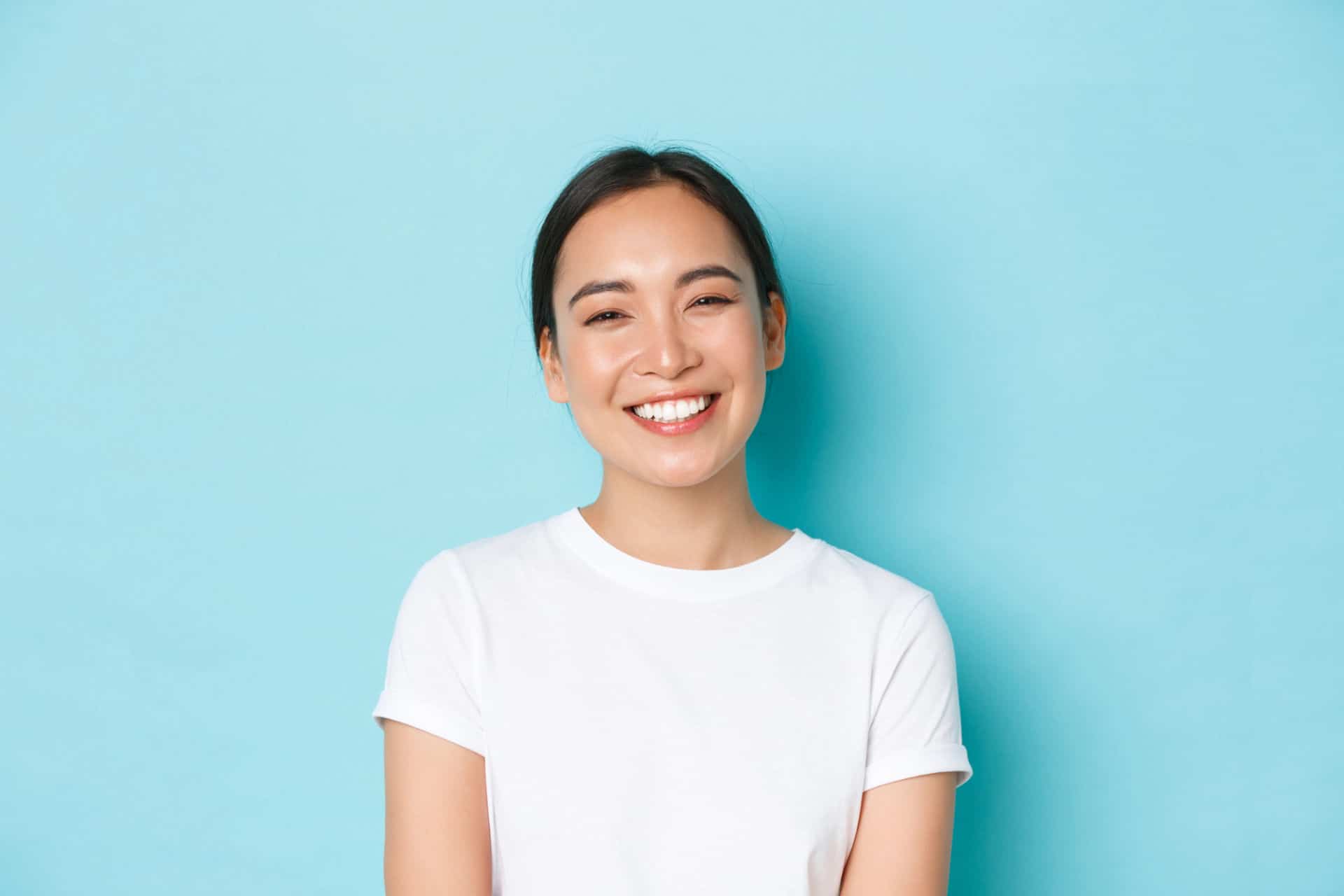 A young woman smiling and showing off her new porcelain veneers.